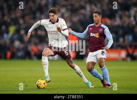 John Stones del Manchester City (a sinistra) e Youri Tielemans dell'Aston Villa si battono per il pallone durante la partita di Premier League a Villa Park, Birmingham. Data foto: Mercoledì 6 dicembre 2023. Foto Stock