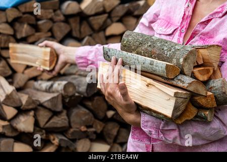 Preparazione per la stagione di riscaldamento con riscaldamento a legna. Legna da ardere nelle mani di una donna. Foto Stock