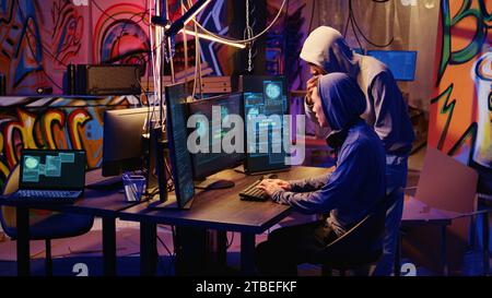 Gli hacker in una base nascosta sono entusiasti di aver superato con successo le misure antimanomissione implementate dalle aziende per proteggere i loro prodotti. I cracker sono contenti dopo aver piratato le versioni di software e videogiochi Foto Stock