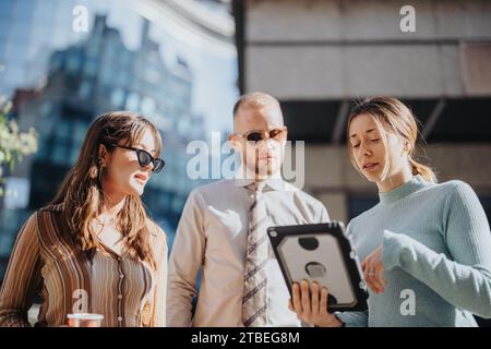 Un team aziendale eterogeneo organizza una strategia all'aperto in città, discutendo delle tendenze del mercato e pianificando l'espansione. Foto Stock