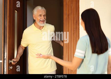 Rapporto amichevole con i vicini. Giovane donna in visita a un uomo anziano Foto Stock