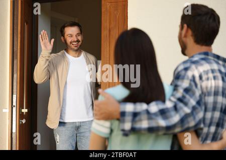 Rapporto amichevole con i vicini. Giovane coppia in visita a un uomo felice Foto Stock