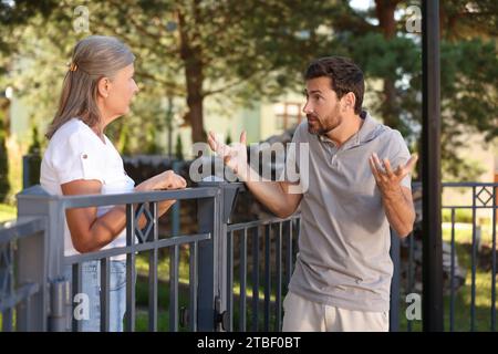 Vicini emotivi che discutono vicino alla recinzione all'aperto Foto Stock