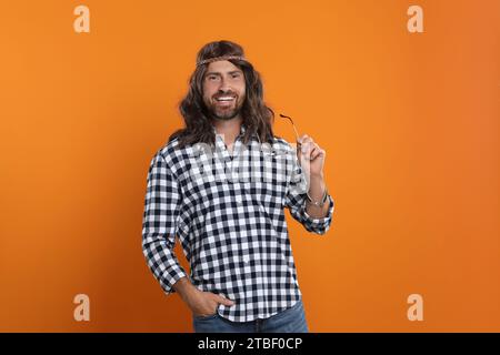 Uomo hippie con occhiali da sole su sfondo arancione Foto Stock