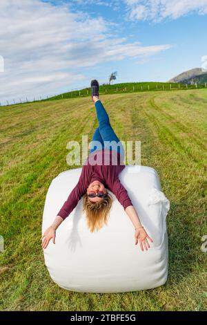 Bella donna di 40 anni che posa su una pila piena di fieno in un ambiente tranquillo Foto Stock
