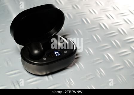 Auricolari bluetooth e wireless neri in una custodia di ricarica. Foto Stock