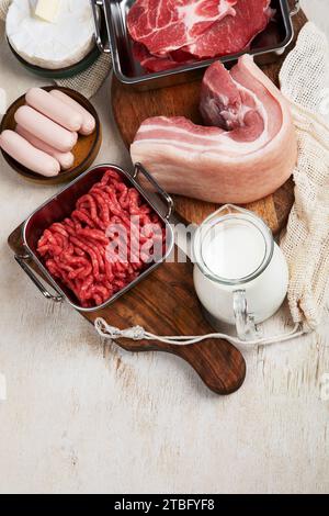 Grassi saturi sui tavoli. Carne cruda, salsicce, formaggio, burro. Cattivo concetto di cibo. Vista dall'alto, spazio di copia. Foto Stock