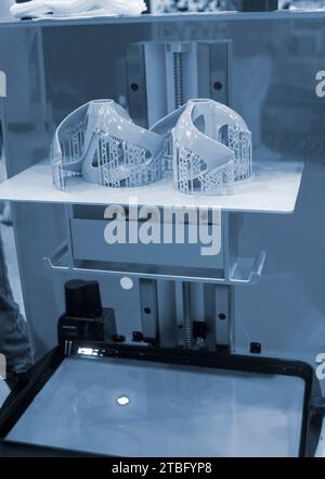 Primi piani dei modelli stampati sulla stampante 3D. Oggetti stampati su stampante 3D sla fotopolimero da resine fotopolimeriche liquide sulla piattaforma di stampa all'interno della stampante 3D. Moderna tecnologia additiva progressiva. Foto Stock