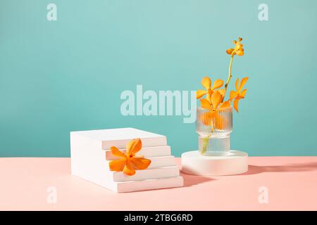 Un ramo di fiori fresco viene posto in una tazza di vetro su un podio bianco. Un fiore d'arancio su una piattaforma terrazzata. Sfondo creativo con due colori rosa e. Foto Stock