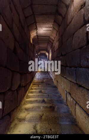 Corridoio illuminato di blocchi di pietra e scale di roccia dall'uscita dell'algive dell'acqua della cittadella araba di Mérida. Provincia di Badajoz, Estremadura Foto Stock