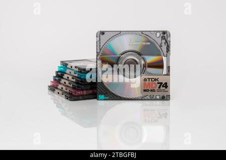 Minidisic TDK MD74 MD-XG è in grado di brillare verticalmente con riflessi iridescenti davanti a una serie di minidisc Foto Stock