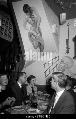 Menschen speisen in einem Pariser Lokal unter einer Wandmalerei, vermutlich am Montmartre im Vergnügungsviertel Pigalle, Parigi 1962. Persone che cenano in un ristorante parigino sotto un murale, probabilmente a Montmartre nel quartiere dei divertimenti di Pigalle, Parigi 1962. Foto Stock