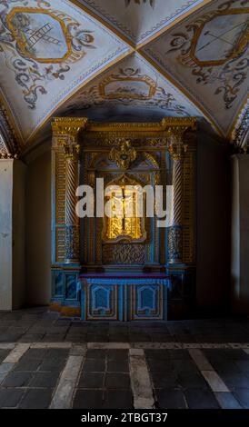 Mobili della cappella decorati lussuosamente con motivi scolpiti in legno color oro con la statua di Gesù Cristo sulla croce illuminata da li dorati Foto Stock