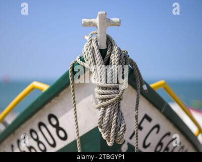 Yport, Francia - 21 luglio 2022: La parte anteriore di un piccolo peschereccio bianco verde che giace sulla spiaggia di Yport, giorno di sole in estate, corda Foto Stock