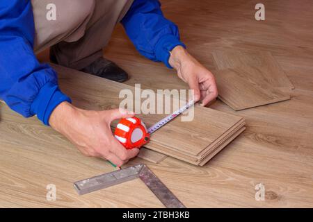 Misurando la lavagna laminata utilizzando un metro a nastro, le mani dei lavoratori misurano un pezzo di lavagna da tagliare nel futuro. Foto Stock