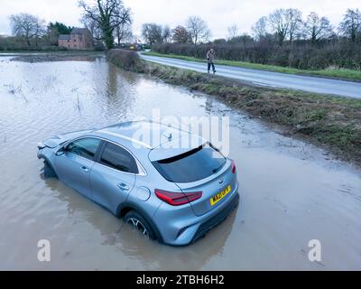 Un'auto esce dalla Old Holly Lane per entrare nei campi allagati vicino ad Atherstone. Il fiume Anker fa scoppiare le sue rive inondando i campi lungo la Sheepy Road sul confine del Warwickshire, Leicestershire. Foto Stock