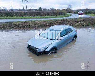 Un'auto esce dalla Old Holly Lane per entrare nei campi allagati vicino ad Atherstone. Il fiume Anker fa scoppiare le sue rive inondando i campi lungo la Sheepy Road sul confine del Warwickshire, Leicestershire. Foto Stock