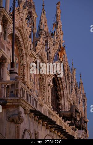 Venezia, la facciata anteriore degli archi della Basilica di San Marco, statue di santi, quattro cavalli, mosaico e sculture in rilievo, balaustra in terrazza alla luce della sera Foto Stock