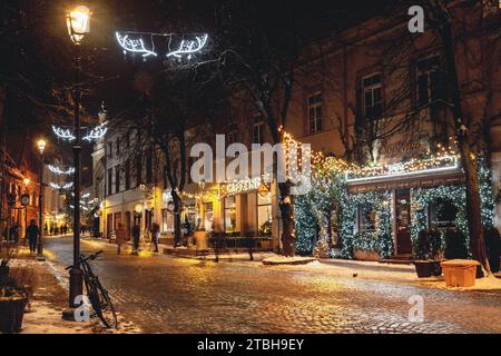 Bellissime decorazioni natalizie, ghirlande, ghirlande e luci nella città vecchia di Vilnius, capitale della Lituania, Europa, di notte con lampioni e bici Foto Stock