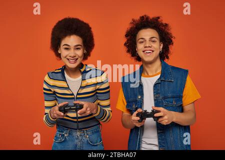 fratello e sorella afro-americani dall'aspetto gradevole che giocano ai videogiochi con joystick, concetto familiare Foto Stock