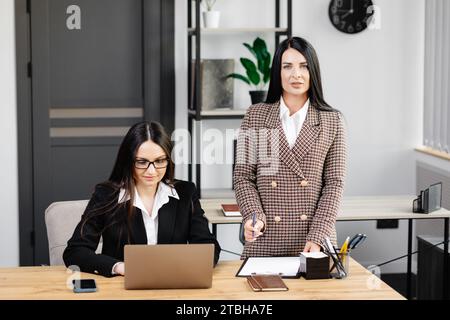 Due giovani donne attraenti lavorano in ufficio. Donne che lavorano a un nuovo progetto, che lavorano su un laptop Foto Stock