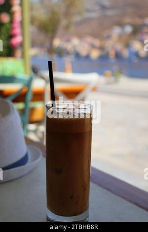 Tradizionale caffè greco freddo Frappe con schiuma di latte, caffè istantaneo e cubetti di ghiaccio in vetro alto primo piano nel caffè. Foto Stock