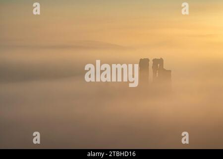 Corfe Castle che emerge dalla nebbia in una fredda mattinata di vento, Dorset, Inghilterra. Inverno (febbraio) 2023. Foto Stock