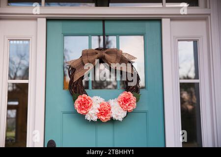 Una corona floreale primaverile su una porta d'acqua blu chiaro di una casa Foto Stock