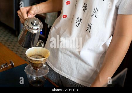 Barista che prepara il caffè in una caffetteria. Primo piano del barista che prepara il caffè all'americana. Foto Stock