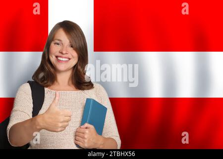 Attraente studentessa con sfondo bandiera danese. Viaggiare, studiare e imparare la lingua in Danimarca concetto Foto Stock