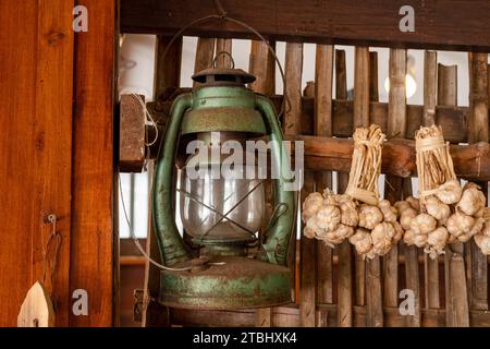 Una vecchia lanterna in cucina pende l'aglio sul muro di bambù. Foto Stock