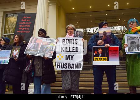 Londra, Regno Unito. 7 dicembre 2023. I manifestanti detengono cartelli anti-Boris Johnson e foto delle vittime del coronavirus durante la manifestazione. I manifestanti e i familiari in lutto si sono riuniti fuori dal Covid-19 Inquiry Hearing Centre mentre l'ex primo ministro Boris Johnson ha dato la sua testimonianza il secondo giorno. (Immagine di credito: © Vuk Valcic/SOPA Images via ZUMA Press Wire) SOLO PER USO EDITORIALE! Non per USO commerciale! Foto Stock