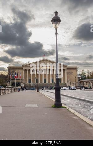 Parigi, Francia, 2023. Persone e automobili che attraversano il Pont de la Concorde verso il Palais Bourbon che ospita l'Assemblea nazionale (verticale) Foto Stock