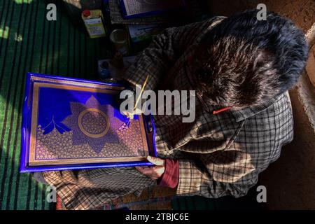 Un artigiano Kashmiri effettua i ritocchi finali su un prodotto in cartapesta prima di inviarlo al mercato in un laboratorio. La cartapesta secolare, una forma d'arte profondamente intrecciata con la cultura e le tradizioni della società Kashmiri, sta morendo lentamente, poiché il numero di persone coinvolte nel commercio è diminuito per varie ragioni. Migliaia di famiglie in Kashmir si guadagnarono da vivere vendendo e facendo oggetti di cartapesta. L'emergere dell'arte della cartapesta accompagnò l'avvento dell'Islam nella regione. Fu introdotto in Kashmir dallo studioso sufi Mir Sayyid Ali Hamdani Foto Stock