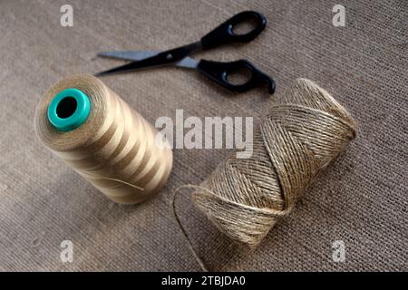 Spighe gialle di filo e forbici su sfondo di rinculo. Filetti e forbici in tessuto grossolano giallo. Foto Stock