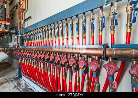 Un rack di valvole e tubi flessibili rossi in una piccola sala di controllo sul tetto di un magazzino di stoccaggio a freddo (refrigerazione industriale) a CO2. Foto Stock