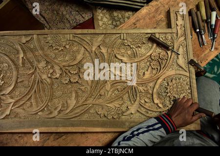 Srinagar, India. 7 dicembre 2023. Un artigiano Kashmiri intaglia un oggetto artigianale in una fabbrica di intaglio del legno. Il Kashmir, il paradiso sulla terra, si riferisce alla bellezza naturale mozzafiato della regione e all'artigianato tradizionale. Insieme a molti altri tipi di arte, il Kashmir è rinomato per la sua tecnica unica di intaglio del legno. L'intaglio in legno Kashmiri è molto richiesto sia all'interno che all'esterno dello stato. Il suo mercato è cresciuto sia a livello locale che globale nel corso degli anni. Ma al giorno d'oggi, gli artigiani stanno lottando per mantenere viva questa arte. La maggior parte dei prodotti realizzati da questi artigiani non ottiene abbastanza profitti, a causa di Foto Stock