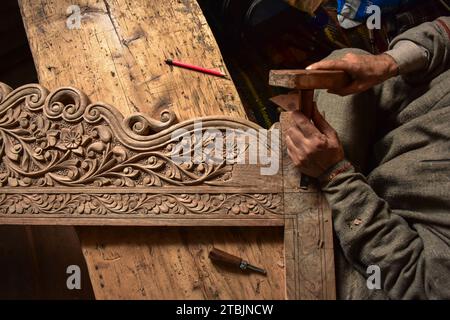 Srinagar, India. 7 dicembre 2023. Un artigiano Kashmiri intaglia un oggetto artigianale in una fabbrica di intaglio del legno. Il Kashmir, il paradiso sulla terra, si riferisce alla bellezza naturale mozzafiato della regione e all'artigianato tradizionale. Insieme a molti altri tipi di arte, il Kashmir è rinomato per la sua tecnica unica di intaglio del legno. L'intaglio in legno Kashmiri è molto richiesto sia all'interno che all'esterno dello stato. Il suo mercato è cresciuto sia a livello locale che globale nel corso degli anni. Ma al giorno d'oggi, gli artigiani stanno lottando per mantenere viva questa arte. La maggior parte dei prodotti realizzati da questi artigiani non ottiene abbastanza profitti, a causa di Foto Stock