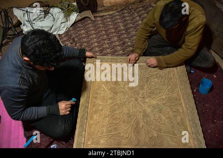 Srinagar, India. 7 dicembre 2023. Gli artigiani Kashmiri intagliano un oggetto artigianale in una fabbrica di intaglio del legno. Il Kashmir, il paradiso sulla terra, si riferisce alla bellezza naturale mozzafiato della regione e all'artigianato tradizionale. Insieme a molti altri tipi di arte, il Kashmir è rinomato per la sua tecnica unica di intaglio del legno. L'intaglio in legno Kashmiri è molto richiesto sia all'interno che all'esterno dello stato. Il suo mercato è cresciuto sia a livello locale che globale nel corso degli anni. Ma al giorno d'oggi, gli artigiani stanno lottando per mantenere viva questa arte. La maggior parte dei prodotti realizzati da questi artigiani non ottiene profitti sufficienti, a causa di W Foto Stock