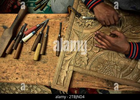 Srinagar, India. 7 dicembre 2023. Un artigiano Kashmiri intaglia un oggetto artigianale in una fabbrica di intaglio del legno. Il Kashmir, il paradiso sulla terra, si riferisce alla bellezza naturale mozzafiato della regione e all'artigianato tradizionale. Insieme a molti altri tipi di arte, il Kashmir è rinomato per la sua tecnica unica di intaglio del legno. L'intaglio in legno Kashmiri è molto richiesto sia all'interno che all'esterno dello stato. Il suo mercato è cresciuto sia a livello locale che globale nel corso degli anni. Ma al giorno d'oggi, gli artigiani stanno lottando per mantenere viva questa arte. La maggior parte dei prodotti realizzati da questi artigiani non ottiene abbastanza profitti, a causa di Foto Stock