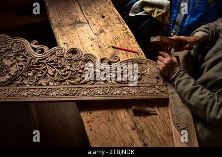 Srinagar, India. 7 dicembre 2023. Un artigiano Kashmiri intaglia un oggetto artigianale in una fabbrica di intaglio del legno. Il Kashmir, il paradiso sulla terra, si riferisce alla bellezza naturale mozzafiato della regione e all'artigianato tradizionale. Insieme a molti altri tipi di arte, il Kashmir è rinomato per la sua tecnica unica di intaglio del legno. L'intaglio in legno Kashmiri è molto richiesto sia all'interno che all'esterno dello stato. Il suo mercato è cresciuto sia a livello locale che globale nel corso degli anni. Ma al giorno d'oggi, gli artigiani stanno lottando per mantenere viva questa arte. La maggior parte dei prodotti realizzati da questi artigiani non ottiene abbastanza profitti, a causa di Foto Stock