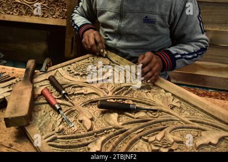 Srinagar, India. 7 dicembre 2023. Un artigiano Kashmiri intaglia un oggetto artigianale in una fabbrica di intaglio del legno. Il Kashmir, il paradiso sulla terra, si riferisce alla bellezza naturale mozzafiato della regione e all'artigianato tradizionale. Insieme a molti altri tipi di arte, il Kashmir è rinomato per la sua tecnica unica di intaglio del legno. L'intaglio in legno Kashmiri è molto richiesto sia all'interno che all'esterno dello stato. Il suo mercato è cresciuto sia a livello locale che globale nel corso degli anni. Ma al giorno d'oggi, gli artigiani stanno lottando per mantenere viva questa arte. La maggior parte dei prodotti realizzati da questi artigiani non ottiene abbastanza profitti, a causa di Foto Stock