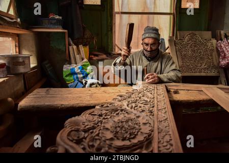 Srinagar, India. 7 dicembre 2023. Un artigiano Kashmiri intaglia un oggetto artigianale in una fabbrica di intaglio del legno. Il Kashmir, il paradiso sulla terra, si riferisce alla bellezza naturale mozzafiato della regione e all'artigianato tradizionale. Insieme a molti altri tipi di arte, il Kashmir è rinomato per la sua tecnica unica di intaglio del legno. L'intaglio in legno Kashmiri è molto richiesto sia all'interno che all'esterno dello stato. Il suo mercato è cresciuto sia a livello locale che globale nel corso degli anni. Ma al giorno d'oggi, gli artigiani stanno lottando per mantenere viva questa arte. La maggior parte dei prodotti realizzati da questi artigiani non ottiene abbastanza profitti, a causa di Foto Stock