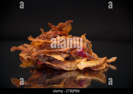 manciata di carne secca marinata con spezie, isolata su fondo nero. Spuntino con birra. Foto Stock