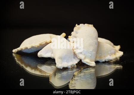 Gnocchi crudi con ripieno all'interno, cucina Ucraina. Gnocchi grezzi per congelare isolati su sfondo nero. Cucina casalinga. Foto Stock