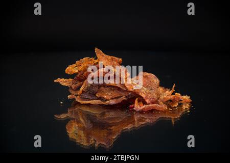 manciata di carne secca marinata con spezie, isolata su fondo nero. Spuntino con birra. Foto Stock