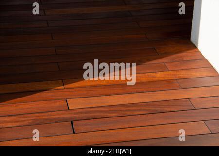 pavimento in legno duro contro parete bianca con luce solare e contrasto ombre Foto Stock