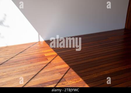 Pavimento interno con struttura in legno cumaru in luce solare e contrasto d'ombra Foto Stock
