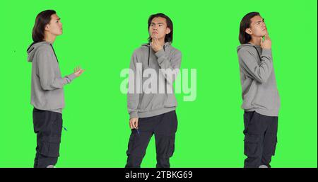 Pensatore maschile che si comporta confuso con la telecamera, pensa a domande e mette a fuoco una nuova prospettiva. Persona incerta e penosa, meditando la soluzione sullo schermo verde. Foto Stock