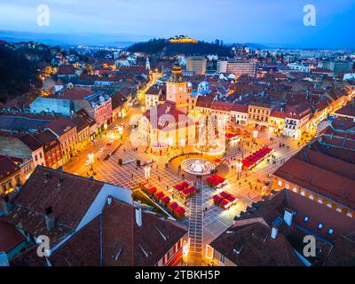 Brasov, Romania. Vista aerea con droni e mercatino di Natale nella piazza principale al crepuscolo, splendida destinazione turistica della Transilvania. Foto Stock